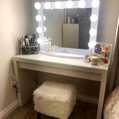 a white vanity with lights on it and a stool