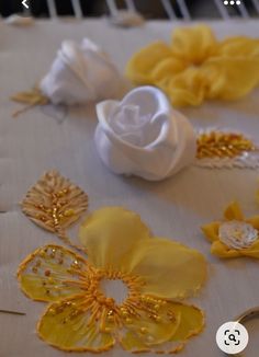 yellow and white fabric flowers on a table with two gold wedding rings next to them