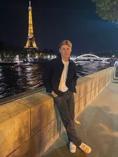 a man leaning against a wall next to the eiffel tower