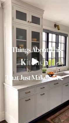 a kitchen with white cabinets and an area rug in front of the window that says things about the kitchen that just make sense