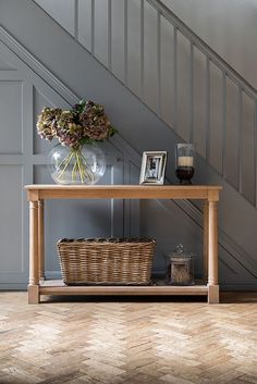 a vase with flowers sitting on top of a wooden table next to a stair case