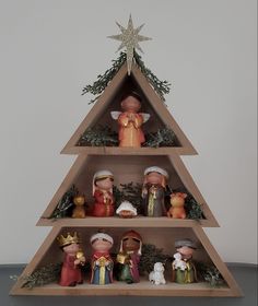 a wooden christmas tree with figurines on it's sides and decorations around the top