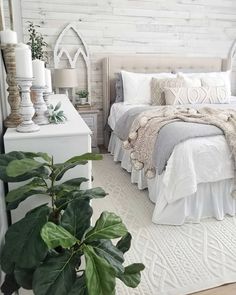 a bedroom with white bedding and green plants on the nightstands next to it