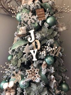 a christmas tree with ornaments and letters on it's top is decorated in green, white