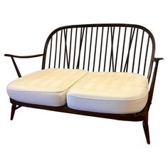 two white cushions sit on top of a wooden bench with black frame and back support