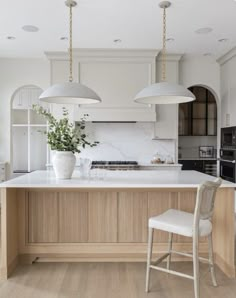 a kitchen with white cabinets and two pendant lights hanging from the ceiling over the island