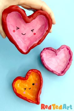 two heart shaped cookies are being held by a child's hand on a blue background