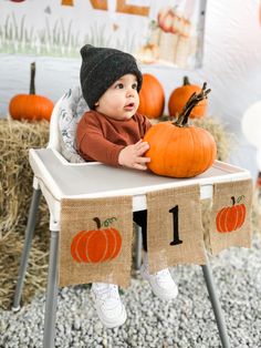 a small child sitting in a high chair with a pumpkin on it's back