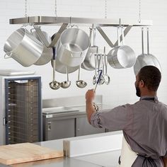 a man is hanging pots and pans from the ceiling