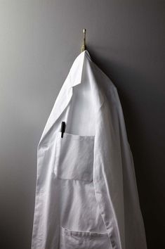 a white shirt hanging on a wall with a small black object in the middle of it