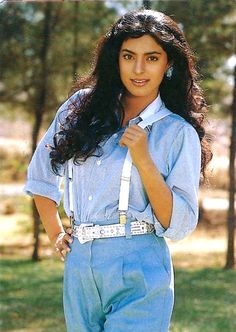 a young woman in overalls posing for a photo with her hands on her hips