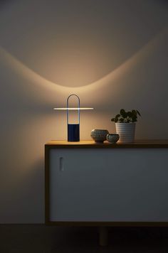 a table with a lamp on top of it next to a bowl and potted plant