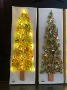 three small christmas trees made out of glass and wood with lights on the sides, sitting next to each other