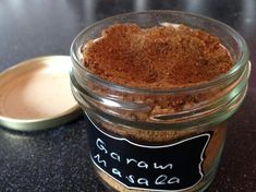 a glass jar filled with brown powder next to a small metal container on top of a table