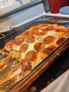 pepperoni and cheese pizza in a glass baking dish on the stove top, ready to be eaten