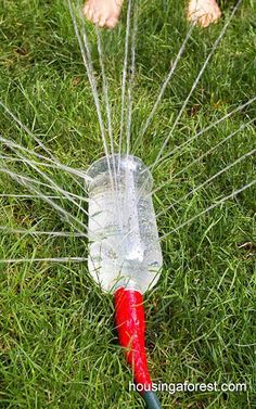 a plastic bottle with water pouring out of it on top of green grass next to a child's feet