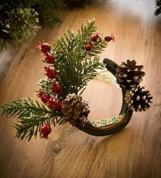 a pine cone wreath with red berries and pine cones on the top is sitting on a wooden table