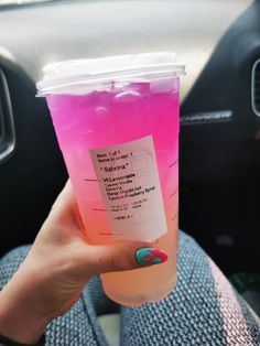 a person holding up a pink drink in their hand