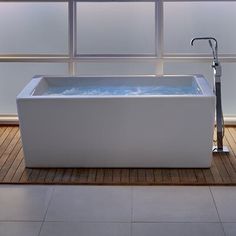 a white bath tub sitting on top of a wooden floor