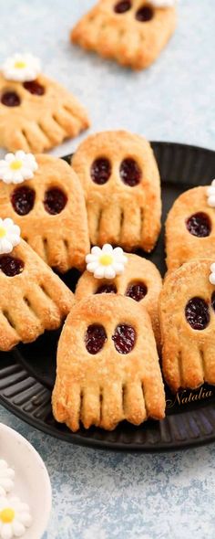 small cookies decorated with jelly and white flowers on a black plate, ready to be eaten