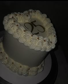 a three tiered cake with white frosting and gold decorations on it's side