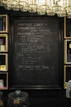 a chalkboard with writing on it in front of shelves filled with bottles and jars