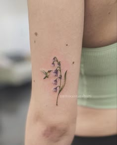 a small flower tattoo on the right arm and leg, with purple flowers growing out of it