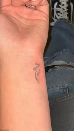 a woman's arm with a small flower tattoo on the left side of her wrist