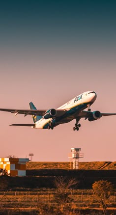 an airplane is taking off from the runway at sunset or dawn with its landing gear down