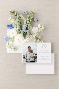 the wedding stationery is laid out on top of an envelope, with blue and white flowers