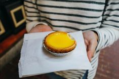 a person holding a small pie in their hand on top of a piece of paper