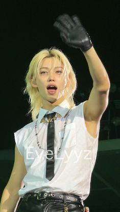 a woman in white shirt and black tie holding her hand up to the air with both hands