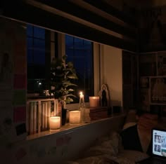 a laptop computer sitting on top of a desk next to a window filled with books