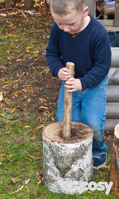 a young boy is playing with an old tree stump