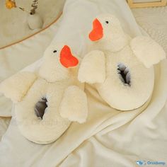 two stuffed ducks sitting on top of a white bed next to eachother with orange beaks