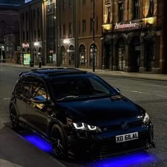 a black car is parked on the side of the road at night with blue lights