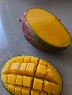 a mango cut in half sitting on top of a counter next to a sliced mango