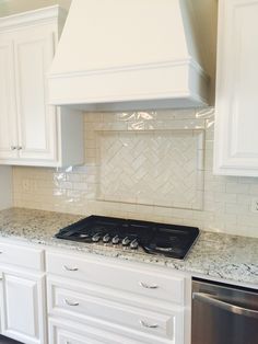 a stove top oven sitting inside of a kitchen next to white cupboards and drawers