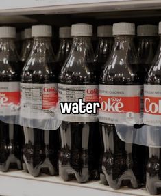 bottles of coke water are on display in a grocery store, with the words coke written above them