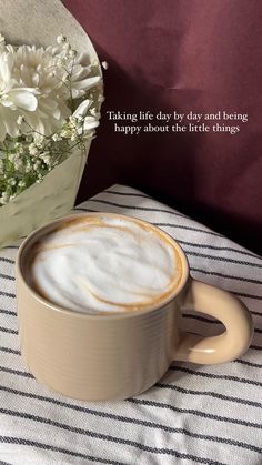 a cup of coffee sitting on top of a table next to a bouquet of flowers