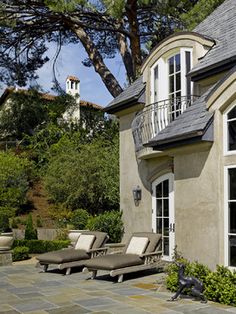 an outdoor patio with chaise lounges and trees in the background