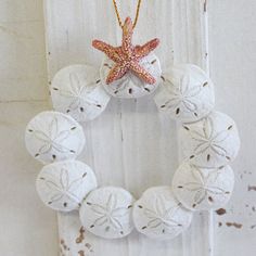 a wreath made out of sand dollars hanging from a door handle with a starfish on it