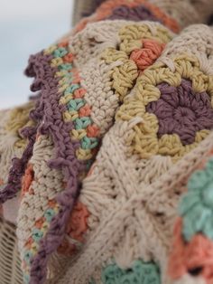 a crocheted blanket sitting on top of a wicker basket