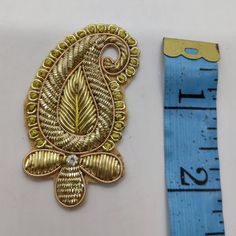 a gold brooch sitting next to a ruler