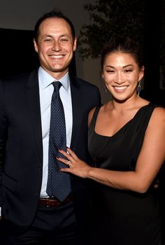 a man and woman standing next to each other in front of a tree at an event