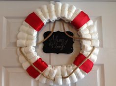 a white wreath with red and white burlocks hanging on the front door