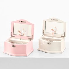 two pink and white jewelry boxes sitting next to each other