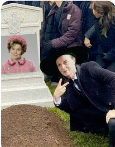 a man in a suit and hat kneeling next to a grave with a woman's face on it