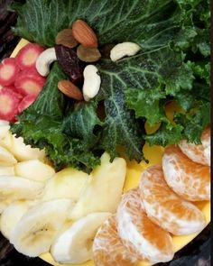 an assortment of fruits and vegetables are arranged on a yellow plate, with almonds in the middle