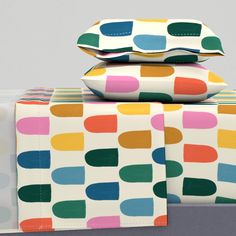 three colorful pillows stacked on top of each other in front of a white wall with polka dots